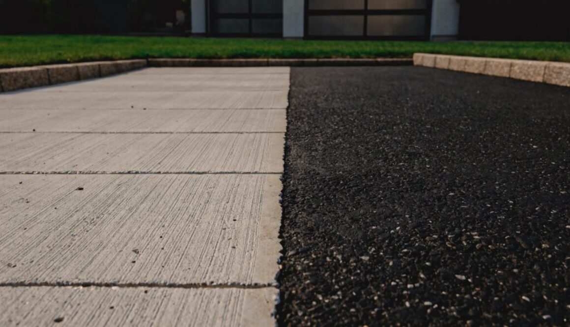 Asphaltieren oder betonieren: Einfahrt mit Betonfläche im Besenstrich neben einer Asphaltfläche, Randsteine und Garage im Hintergrund
