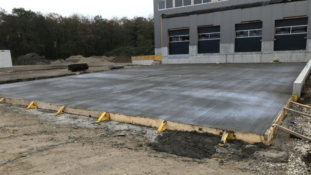 Frisch betonierte Bodenplatte in der Schalung vor einer Gewerbehalle – Festigkeitsklassen wie Beton C16/20 und C20/25 richtig wählen