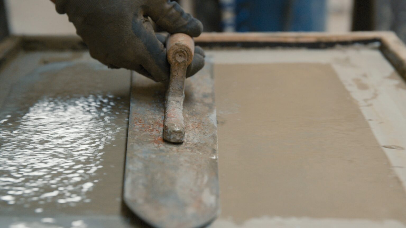 Beton wird nicht hart: frischer Beton mit Wasser an der Oberfläche wird mit der Glättkelle abgezogen