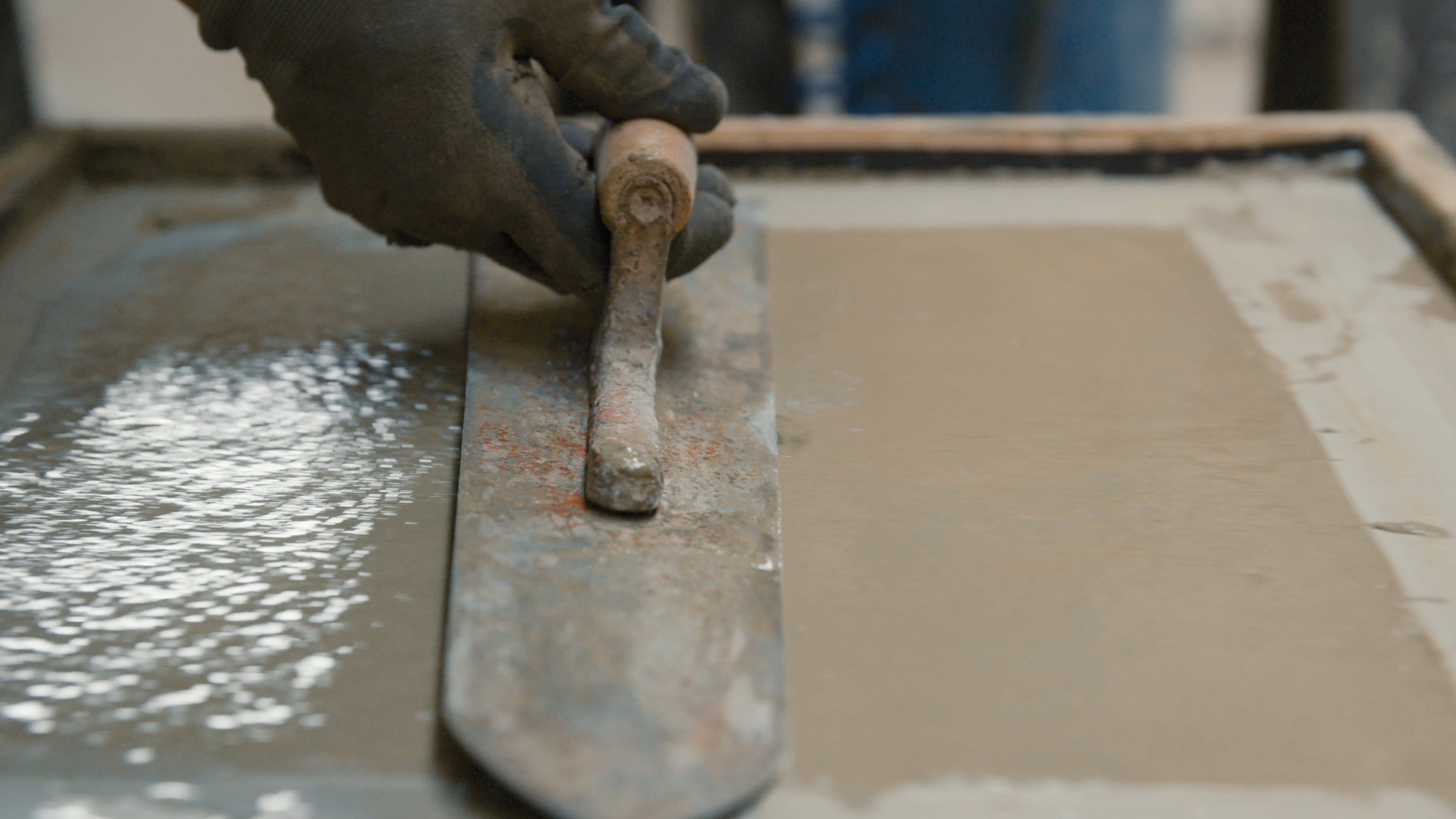 Beton wird nicht hart: frischer Beton mit Wasser an der Oberfläche wird mit der Glättkelle abgezogen