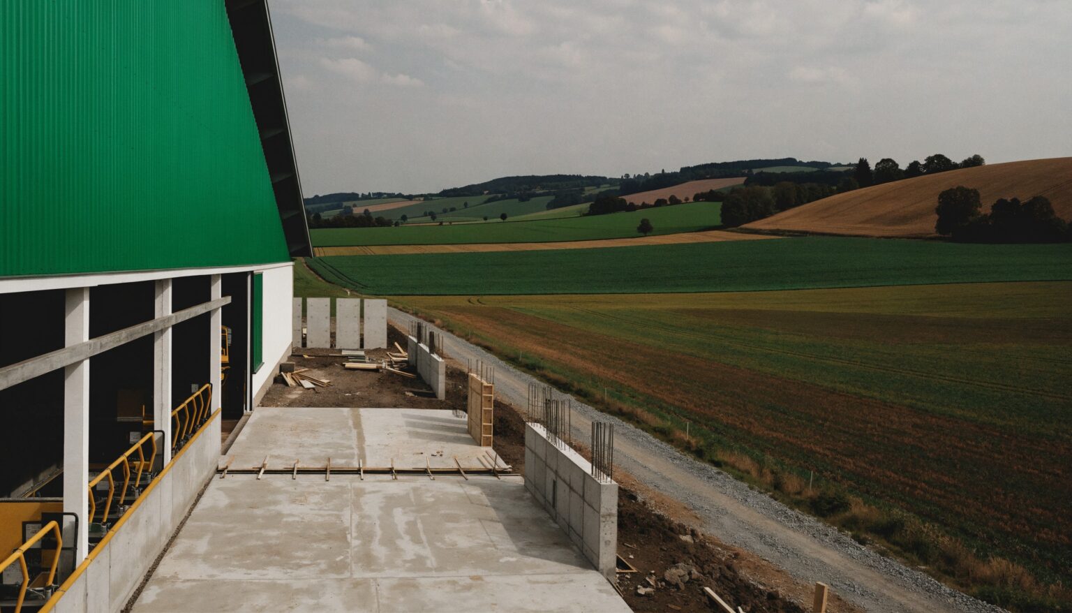 Stall umbauen: Erweiterung eines Rinderstalls im Rohbau mit Bodenplatte, Betonsockeln und Schalung neben dem bestehenden Stall