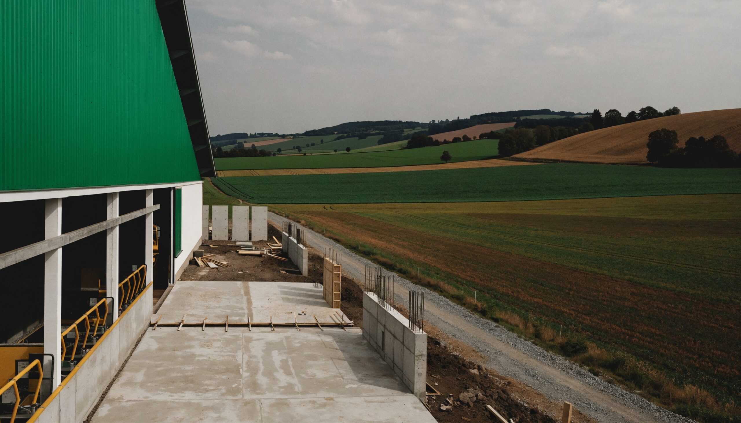 Stall umbauen: Erweiterung eines Rinderstalls im Rohbau mit Bodenplatte, Betonsockeln und Schalung neben dem bestehenden Stall